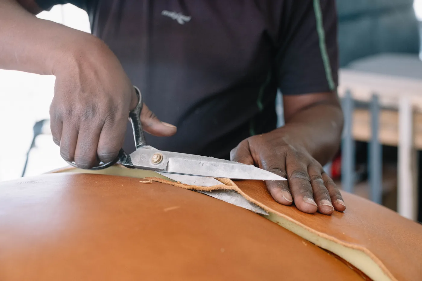 Craftsperson cutting leather for custom furniture